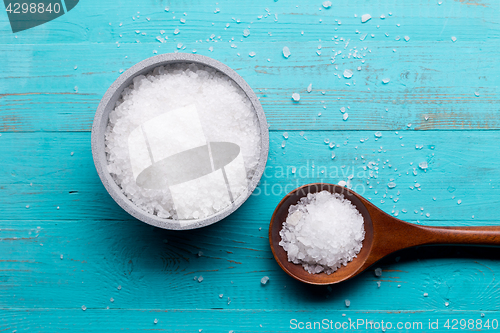 Image of sea salt in bowl and in spoon on wooden background