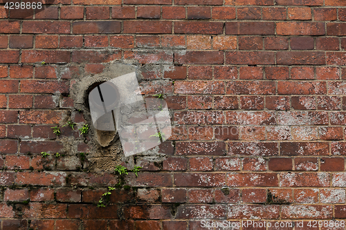 Image of Old red brick wall with pipe