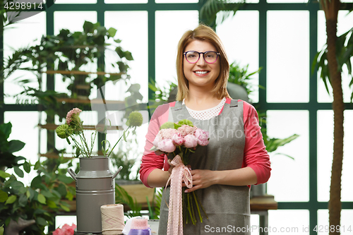 Image of Young smiling florist in greenhouse