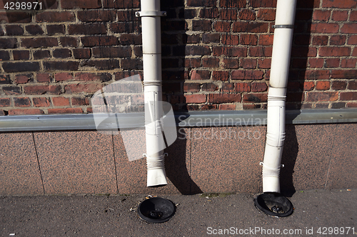 Image of two old drainpipes on a brick wall