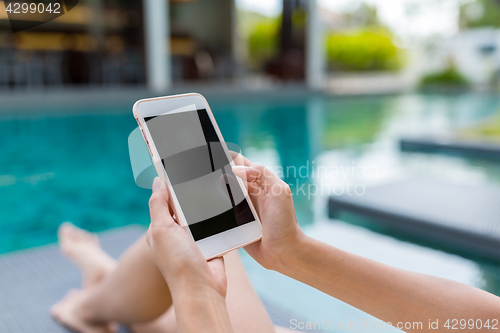 Image of Young Woman using mobile phone in swimming pool