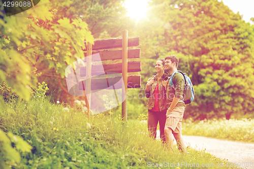 Image of smiling couple at signpost with backpacks hiking