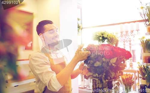 Image of smiling florist man with roses at flower shop