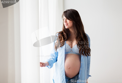 Image of happy pregnant woman with big tummy at home