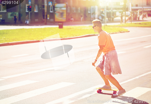 Image of teenage boy on skateboard crossing city crosswalk