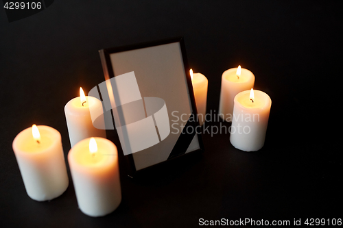 Image of photo frame with black mourning ribbon and candles