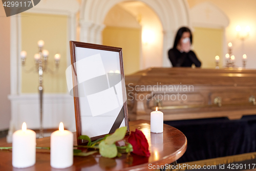 Image of photo frame and woman crying at coffin at funeral