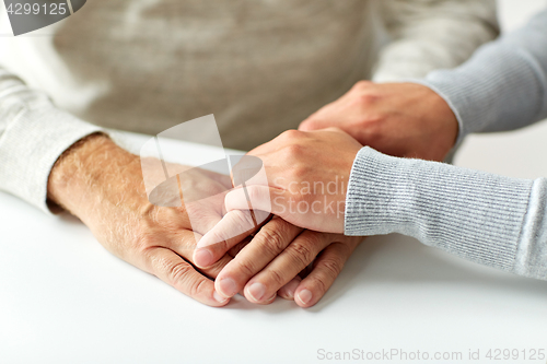 Image of close up of old man and young woman holding hands