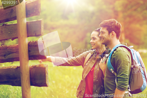 Image of smiling couple at signpost with backpacks hiking