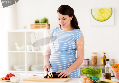 Image of pregnant woman cooking vegetables at home