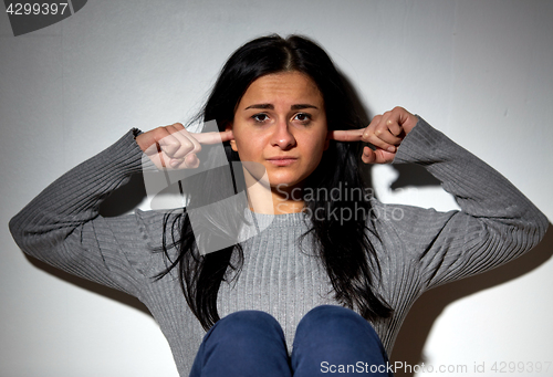 Image of unhappy woman closing ears by fingers