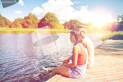 Image of happy teenage couple sitting on river berth