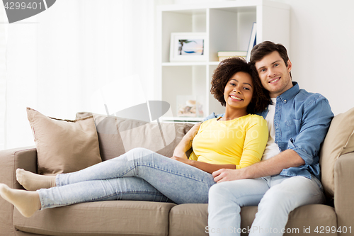 Image of happy smiling international couple on sofa at home