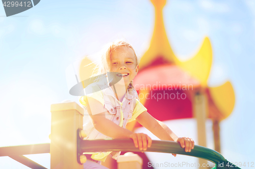 Image of happy little girl climbing on children playground