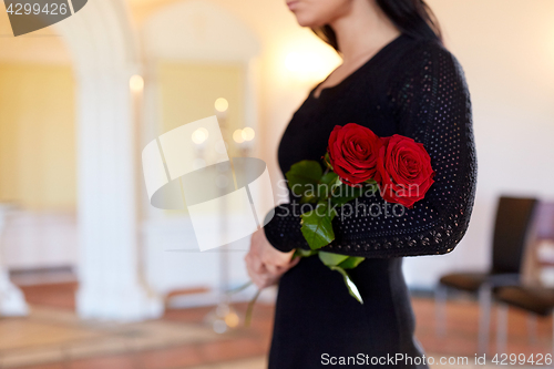 Image of woman with red roses at funeral in church