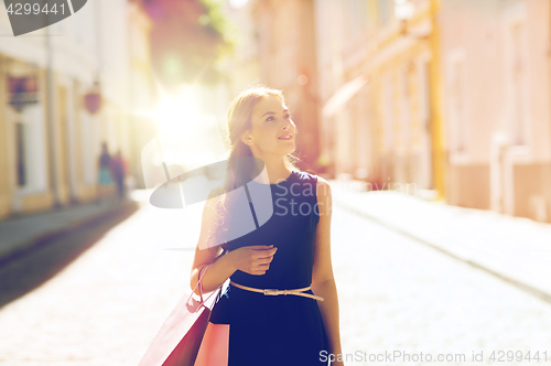 Image of happy woman with shopping bags walking in city 