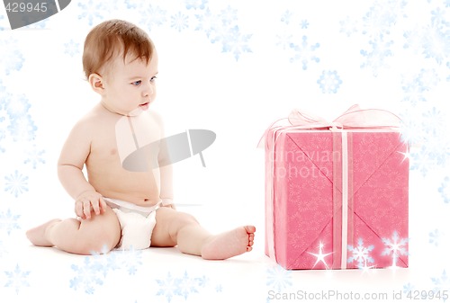 Image of baby boy in diaper with big gift box and snowflakes