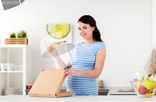 Image of happy pregnant woman eating pizza at home kitchen