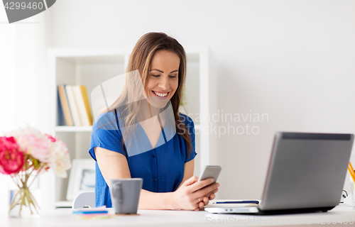 Image of woman with smartphone and laptop at office