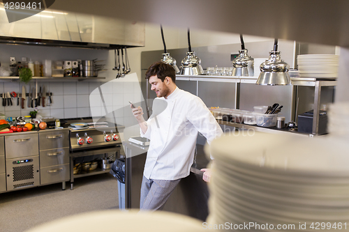 Image of chef cook with smartphone at restaurant kitchen