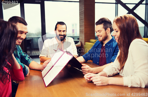 Image of smiling friends discussing menu at restaurant