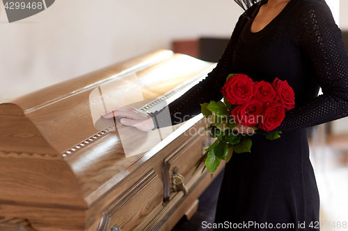 Image of woman with red roses and coffin at funeral