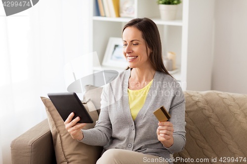 Image of happy woman with tablet pc and bank card at home