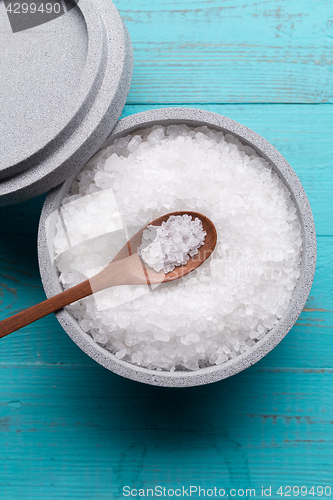 Image of Sea salt in an stone bowl with small wooden spoon on a blue wooden table