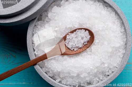 Image of Sea salt in an stone bowl with small wooden spoon on a blue wooden table