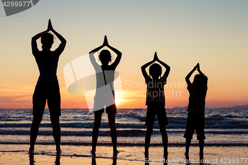 Image of Mother and children playing on the beach at the sunset time.