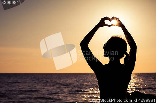 Image of woman open arms under the sunset at sea. 