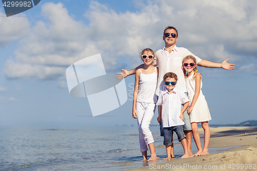 Image of Father and children playing on the beach at the day time.