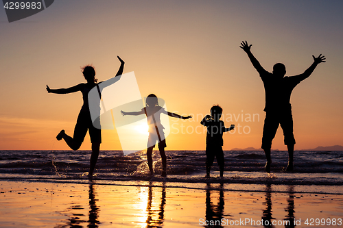 Image of Silhouette of happy family who playing on the beach at the sunse