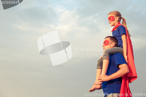 Image of Father and daughter playing superhero at the day time. 