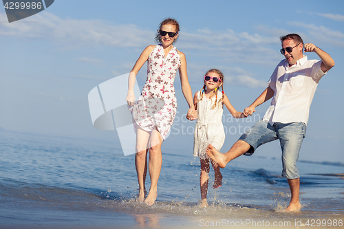 Image of Happy family walking on the beach at the day time.