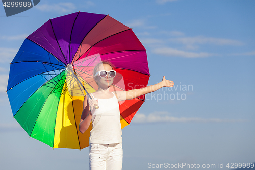 Image of Ten girl with umbrella standing on the beach