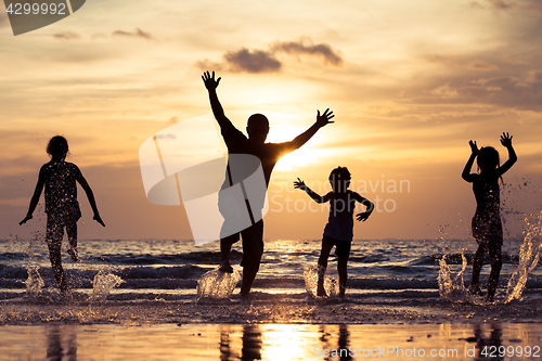 Image of Father and children playing on the beach at the sunset time.