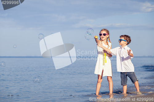 Image of Sister and brother playing on the beach at the day time. 