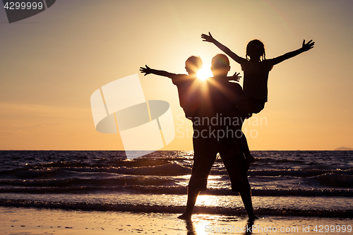 Image of Father and children playing on the beach at the sunset time.