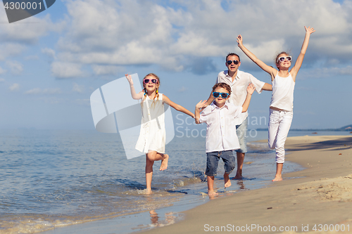 Image of Father and children playing on the beach at the day time.