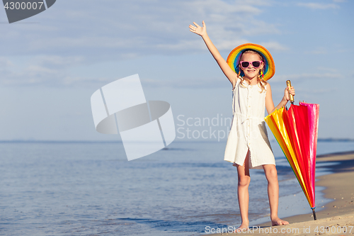 Image of little girl with umbrella standing on the beach