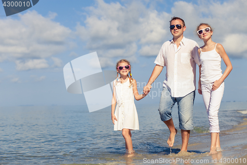 Image of Father and children sitting on the beach at the day time.