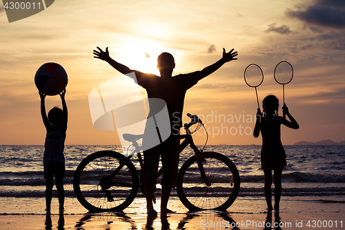 Image of Father and children playing on the beach at the sunset time.