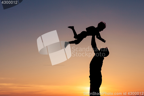 Image of Father and son playing on the beach at the sunset time.