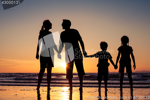 Image of Silhouette of happy family who playing on the beach at the sunse