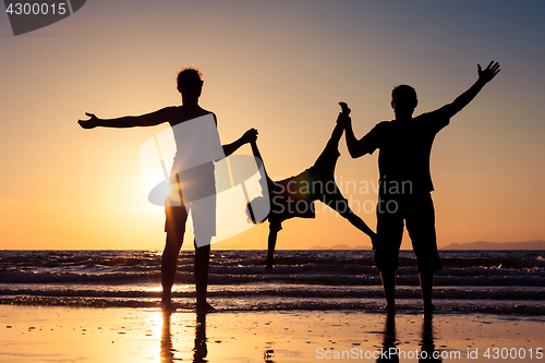 Image of Silhouette of happy family who playing on the beach at the sunse