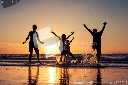 Image of Silhouette of happy family who playing on the beach at the sunse