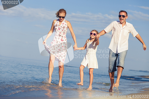 Image of Happy family walking on the beach at the day time.