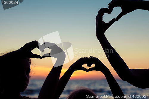 Image of Mother and children playing on the beach at the sunset time.