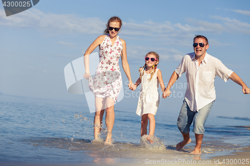 Image of Happy family walking on the beach at the day time.